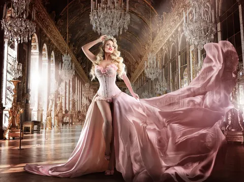 Client in pink gown on ornate castle balcony with dramatic pink silk train fabric