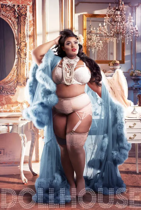 Curvy woman in ivory lace lingerie and pearls wearing a flowing blue marabou robe in a Hollywood-style dressing room