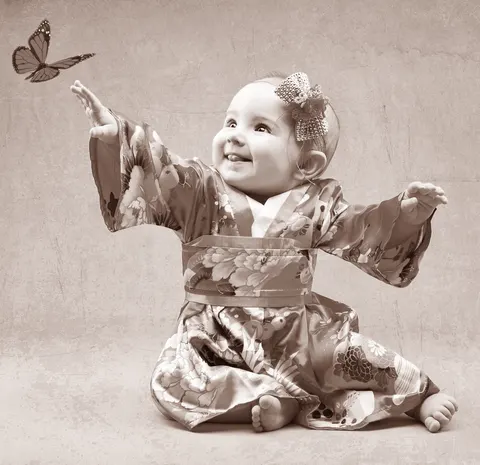 Baby in metallic vintage outfit reaching towards butterfly decoration