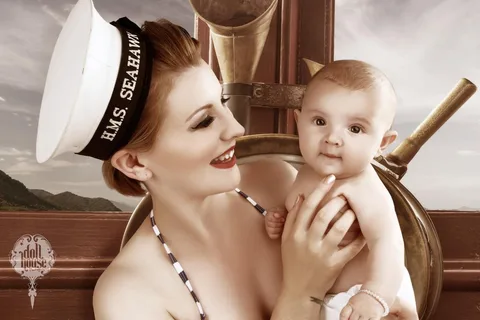 Mother in a sailor hat smiling with her baby on a ship's deck
