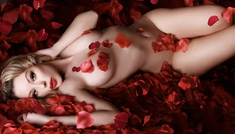 Blonde woman reclining gracefully on red rose petals